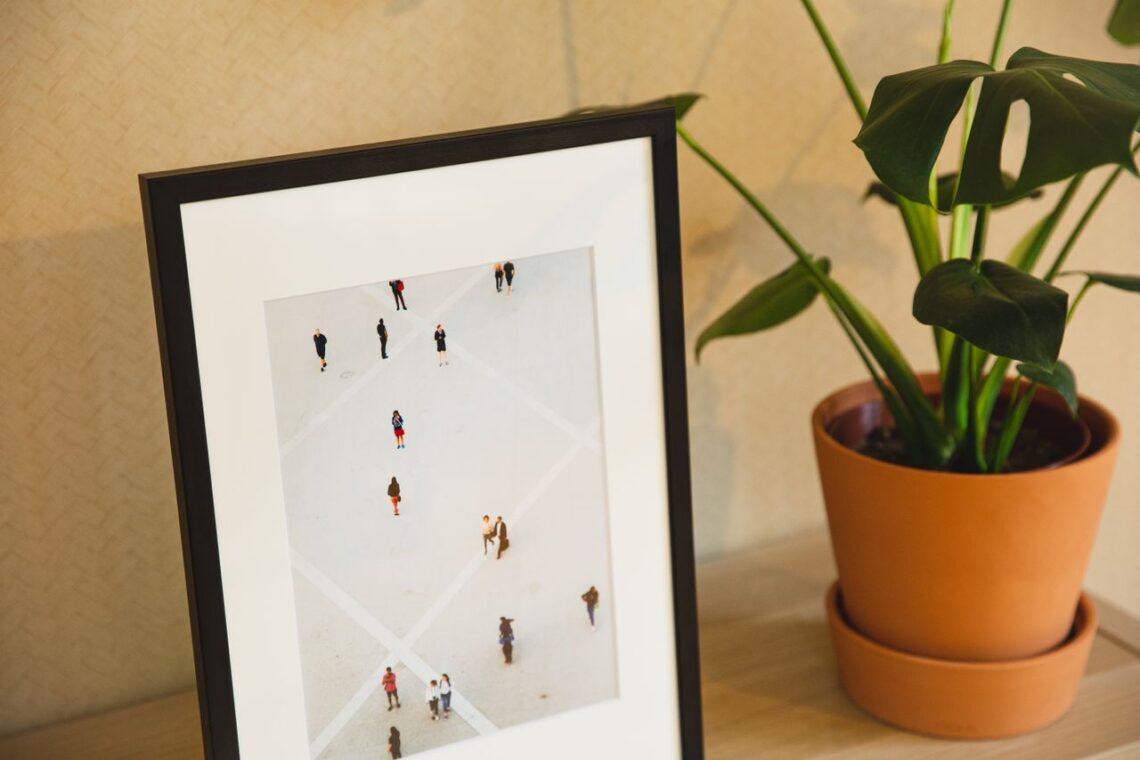 A modern interior featuring a framed art piece and a lush potted plant on a table.